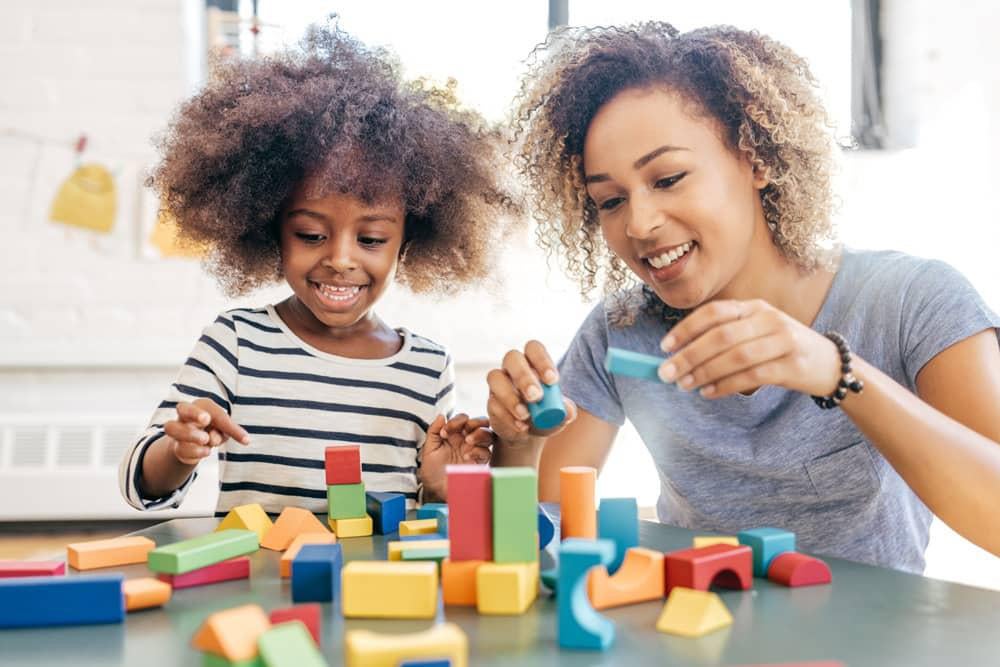 Mãe e filha brincam com blocos de montar para favorecer o desenvolvimento infantil.