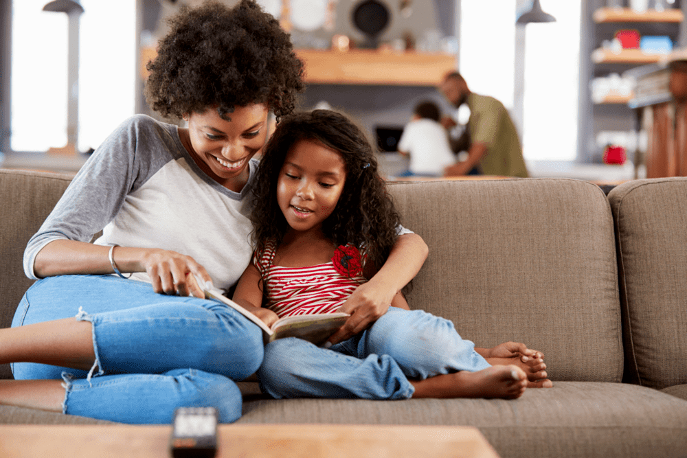 Mãe e filha lêem juntas, um tipo de brincadeira para criança.