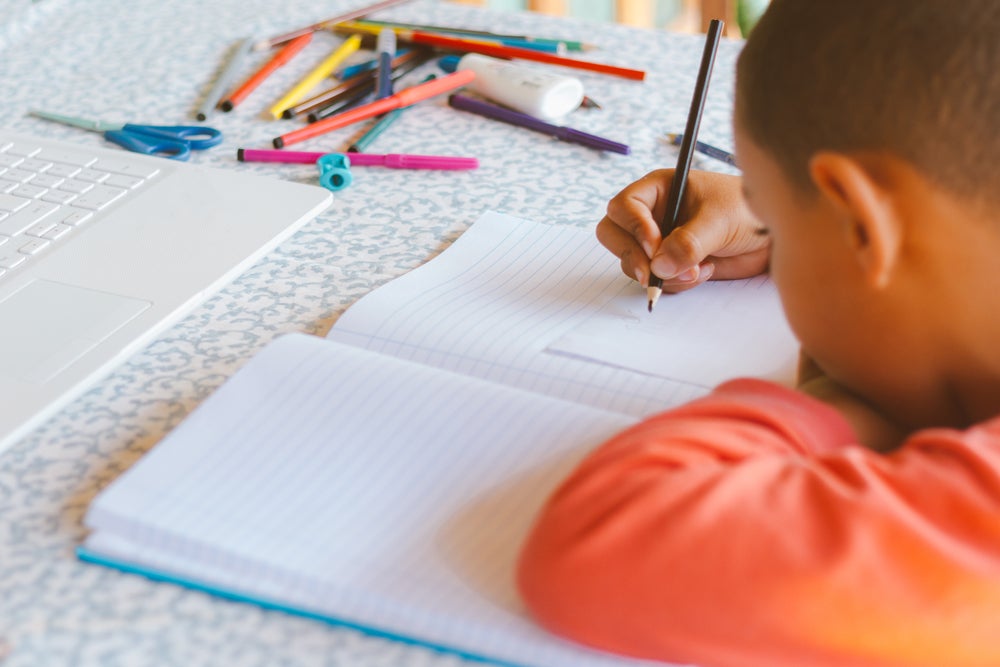 menino escrevendo em um caderno