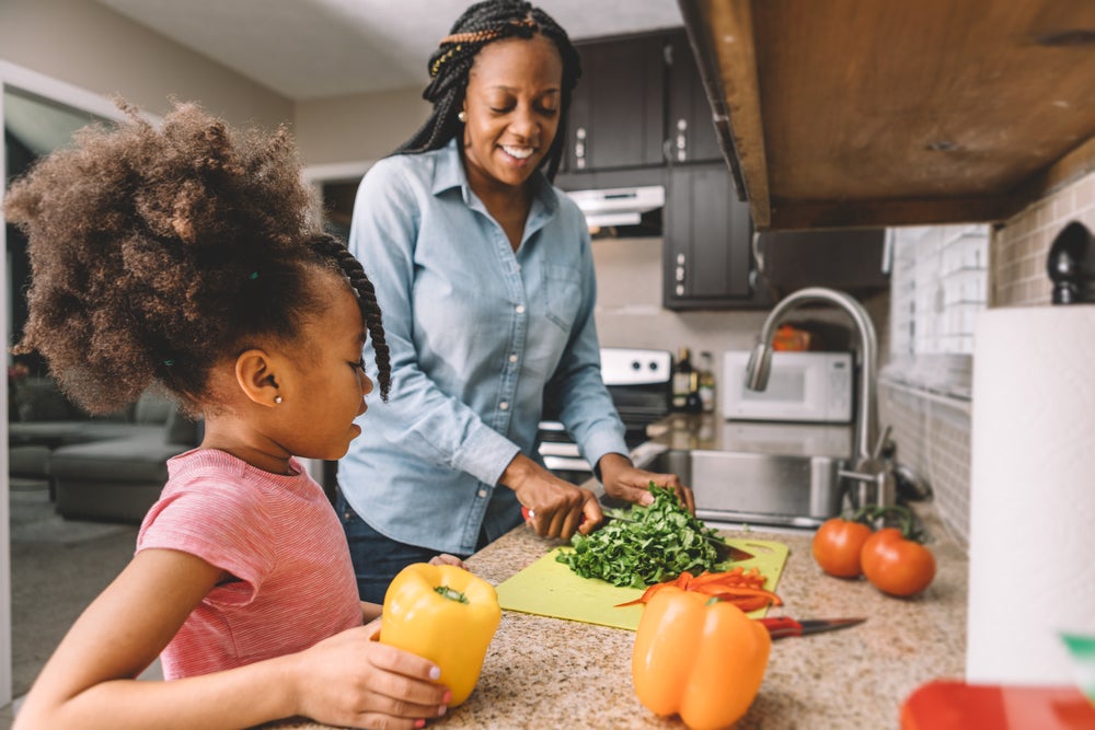 Mãe e filha na cozinha preparando refeição com alimentos ricos em ferro