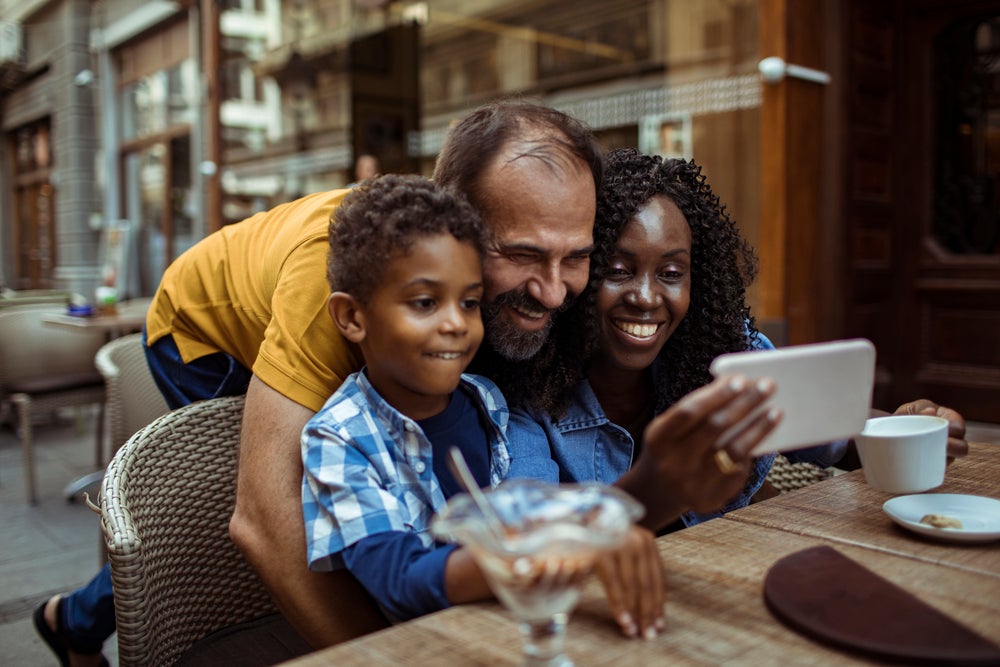 Um exemplo de como ser uma boa madrasta: uma mulher se diverte em um café com o marido e o enteado, e eles tiram foto juntos.