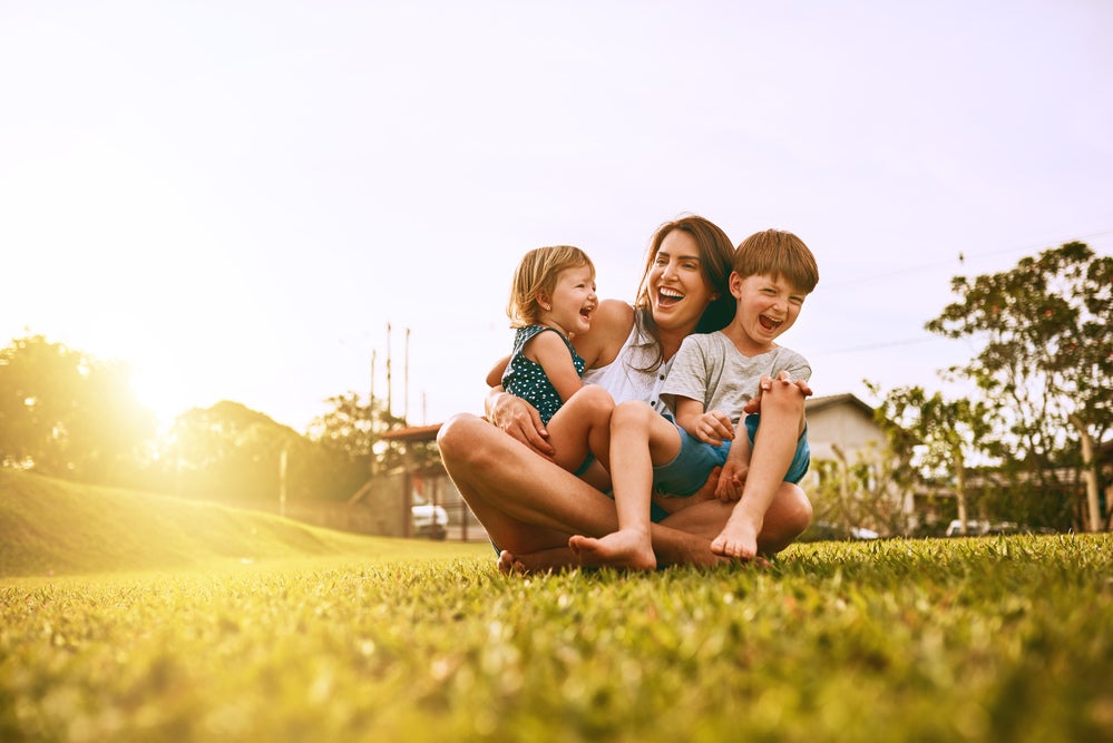 "mãe reunida com dois filhos em um ambiente aberto"