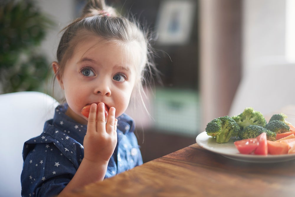 Foto de uma menina comendo verduras 