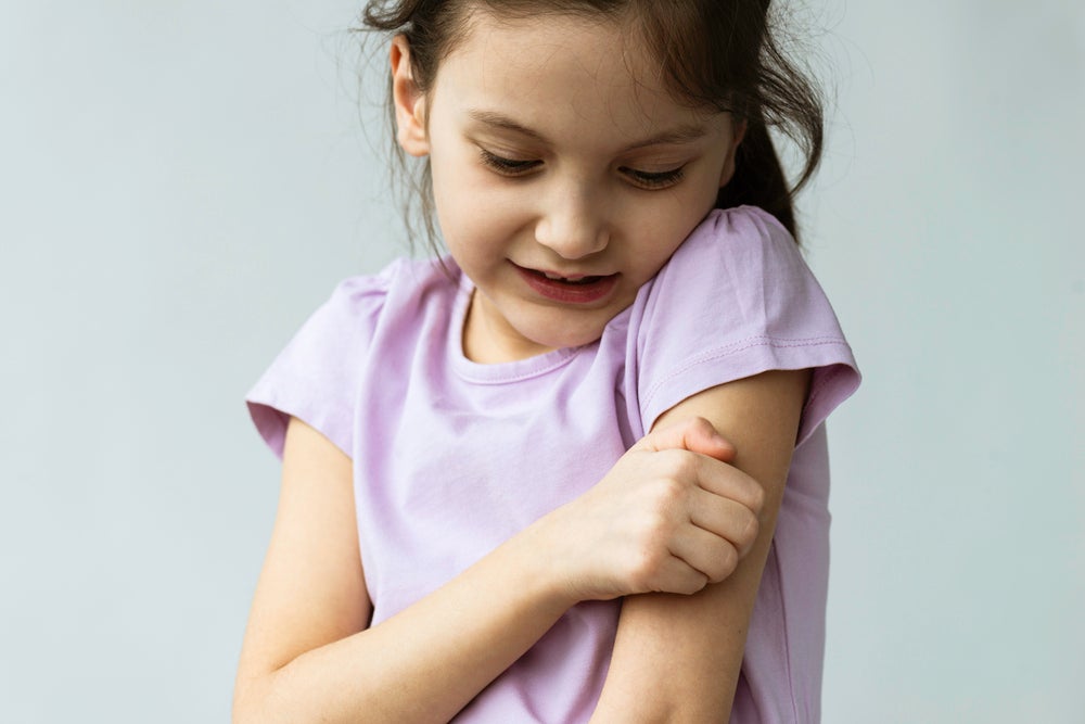 Imagem de uma criança coçando o próprio braço, a coceira pode ser um dos sintomas de alergia emocional.