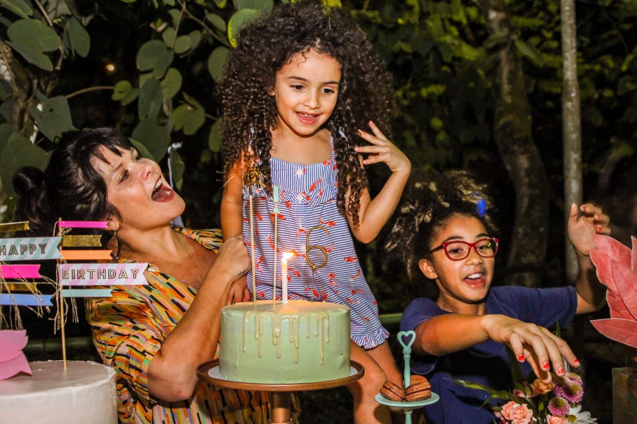 Samara Felippo com as suas duas filhas, elas estão em uma festa de aniversário e na goto podemos ver o bolo com as velas.