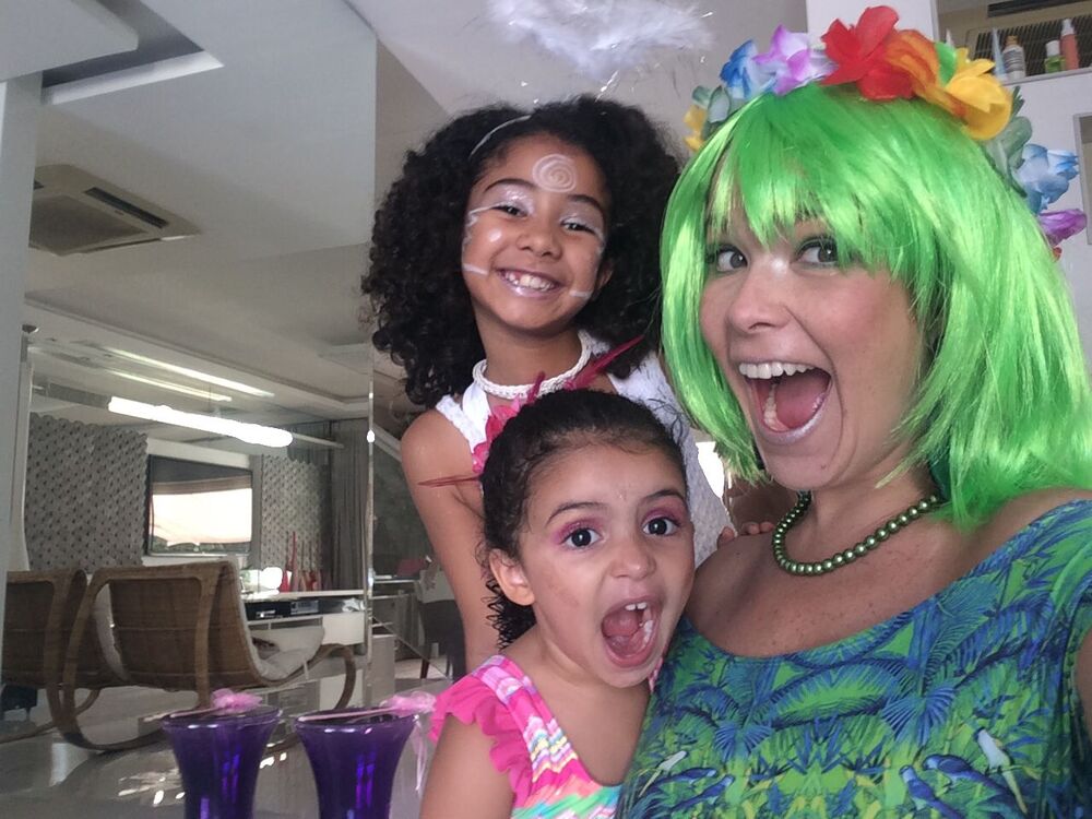 Samara Felippo sorri para a foto com suas duas filhas, na sala de casa, as três usam fantasias.