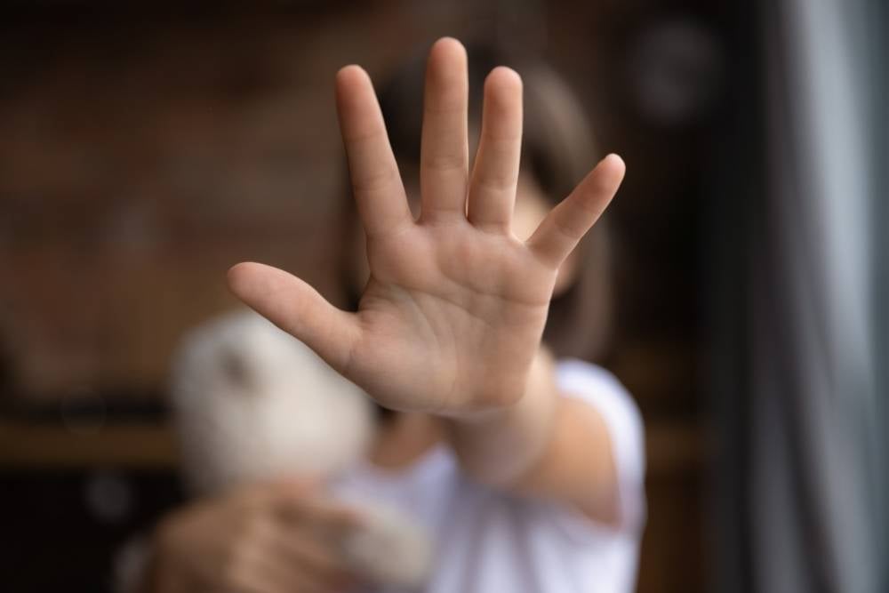 Uma criança estende a mão aberta para a câmera, um dos símbolos da luta contra o bullying nas escolas. 