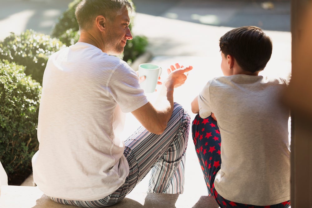 pai e filho sentados na calçada conversando
