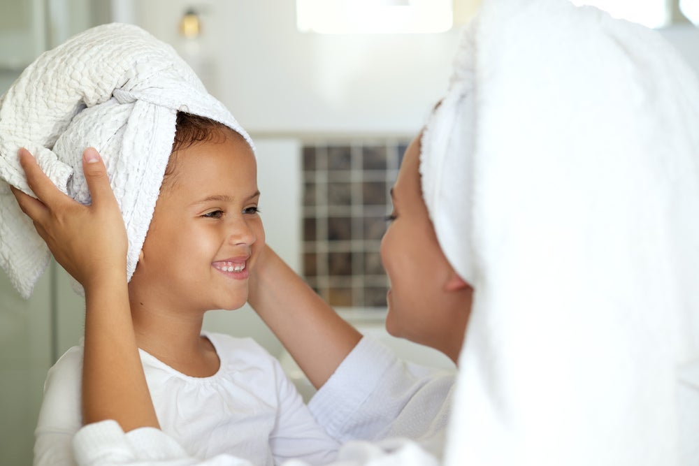 mãe e filha com toalhas na cabeça pós banho