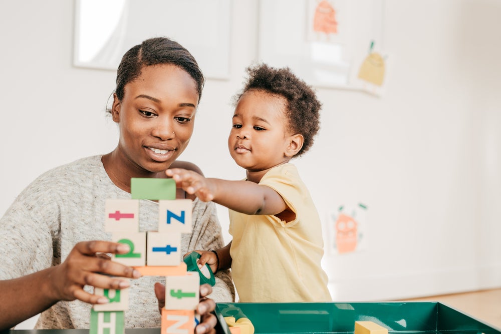 Mulher com um garotinho brincando de empilhar cubinhos educativos