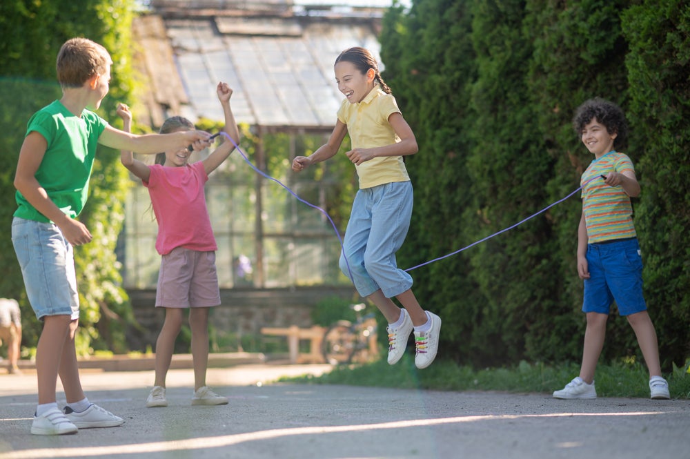 Quatro crianças brincando de pular corda ao ar livre 