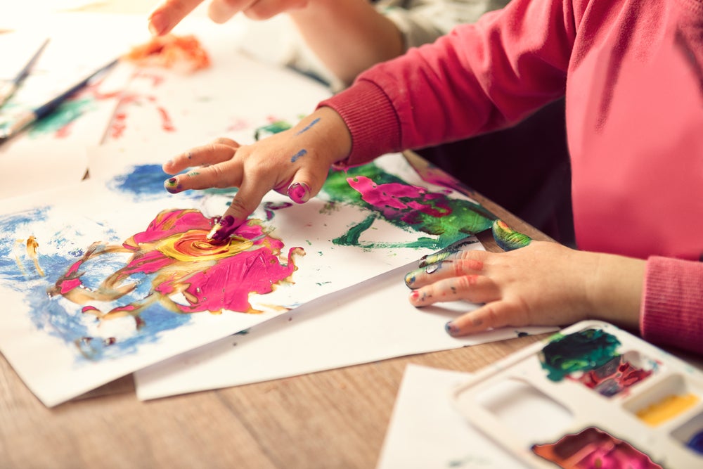 Mão de criança colorindo um papel com tinta