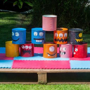 Em ambiente externo, 10 latas de ninho estão customizadas com rostos de monstrinhos e empilhadas sobre um pallet.