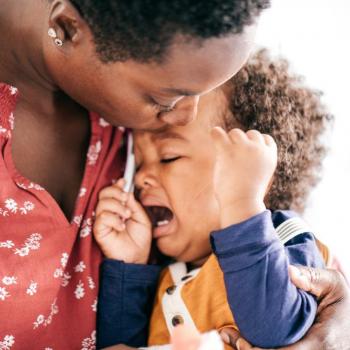 Mãe consola o filho que chora e faz birra em seu colo.