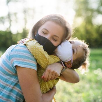 Mãe na pandemia: 5 dicas para manter a sua saúde mental Um abraço de mãe e filha, ambas de máscara e ao ar livre, indica um momento que revigora a saúde mental.