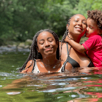 A música na vida dos meus filhos, meus filhos na minha música Dentro de um lago, a cantora Negra Li, ilustra a importância da música para crianças. Ela está segurando um filho no colo e em frente está sua outra filha.