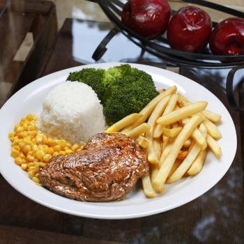 Sobre uma mesa estão um arranjo com três maçãs e um prato com arroz, milho, carne, brócolis e batatas fritas. Representam as comidas típicas do Brasil.