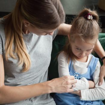 Sentadas em um sofá verde, a mãe tenta dialogar com a filha que está emburrada de braços cruzados.