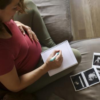 Mulher grávida faz uma lista em caderno com nomes de criança para seu bebê