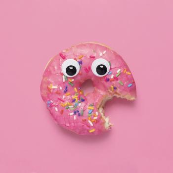 Imagem de um donut rosa com olhinhos e um pedaço mordido representando o rostinho de uma criança obesa