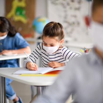 Crianças de máscara aprendendo com uma metodologia de ensino e estudando em uma sala de aula. 