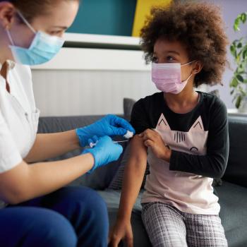 Criança de máscara recebendo dose de vacina