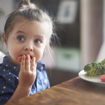 Foto de uma menina comendo verduras 