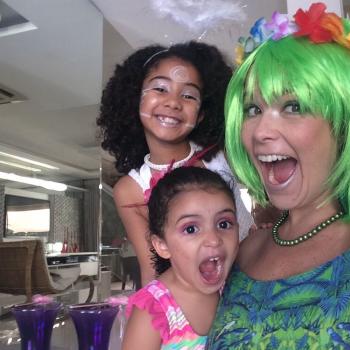 Samara Felippo sorri para a foto com suas duas filhas, na sala de casa, as três usam fantasias.