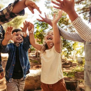 19 brincadeiras para crianças de 8 anos para fazer em família Crianças sorridentes num parque, brincando ao ar livre com bolhas de sabão