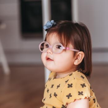 Criança sentada no chão de casa utilizando óculos