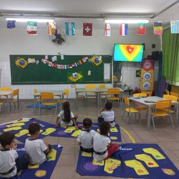 Crianças sentadas numa sala de aula assistindo a televisão 