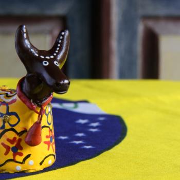 Imagem de um objeto do bumba meu boi, em cima da bandeira do Brasil representando o folclore 