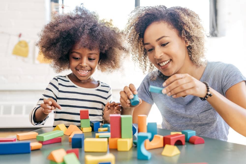 Mãe e filha brincam com blocos de montar para favorecer o desenvolvimento infantil.