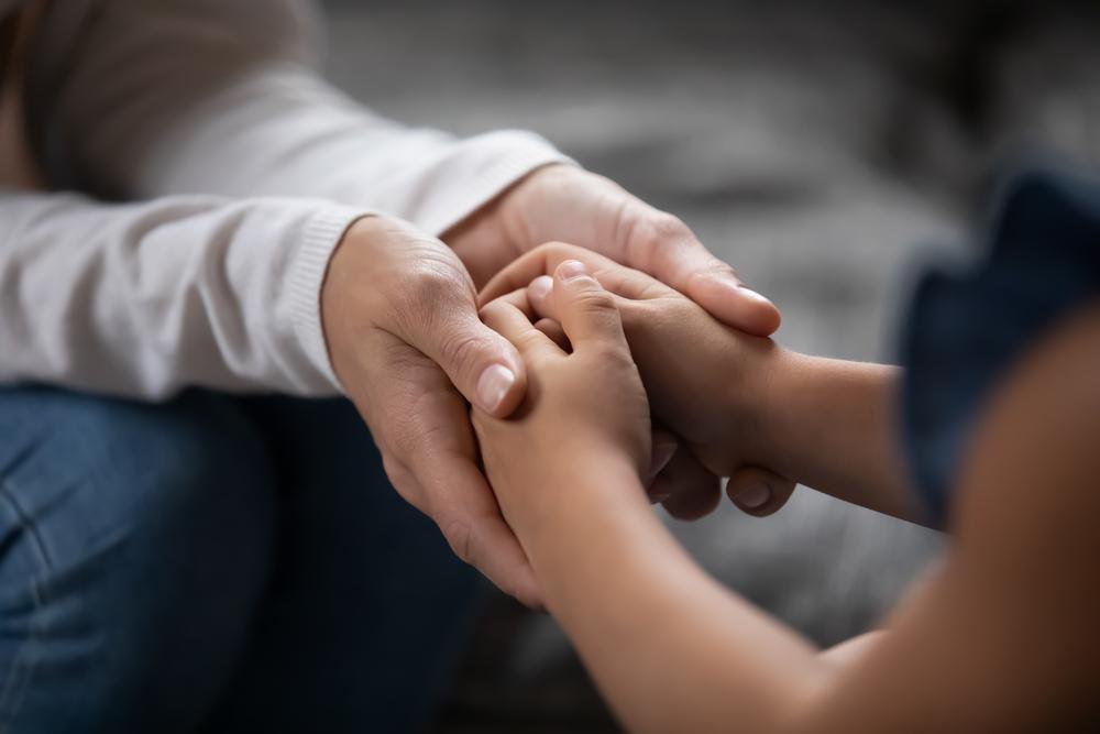 Mãe de mãos dadas om a criança. Foco nas mãos entrelaçadas