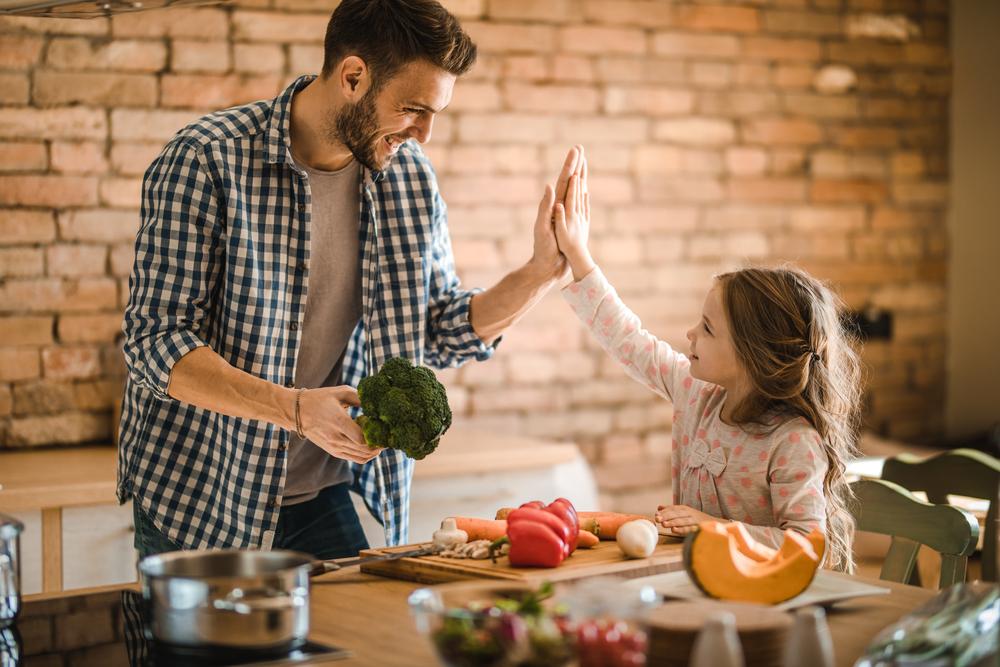Pai e uma criança vegetariana cozinham apenas com legumes e vegetais. 