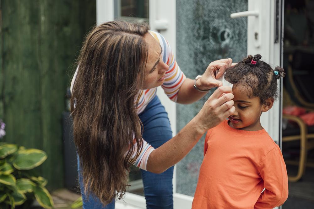 Mãe faz um curativo em criança que bateu a cabeça.