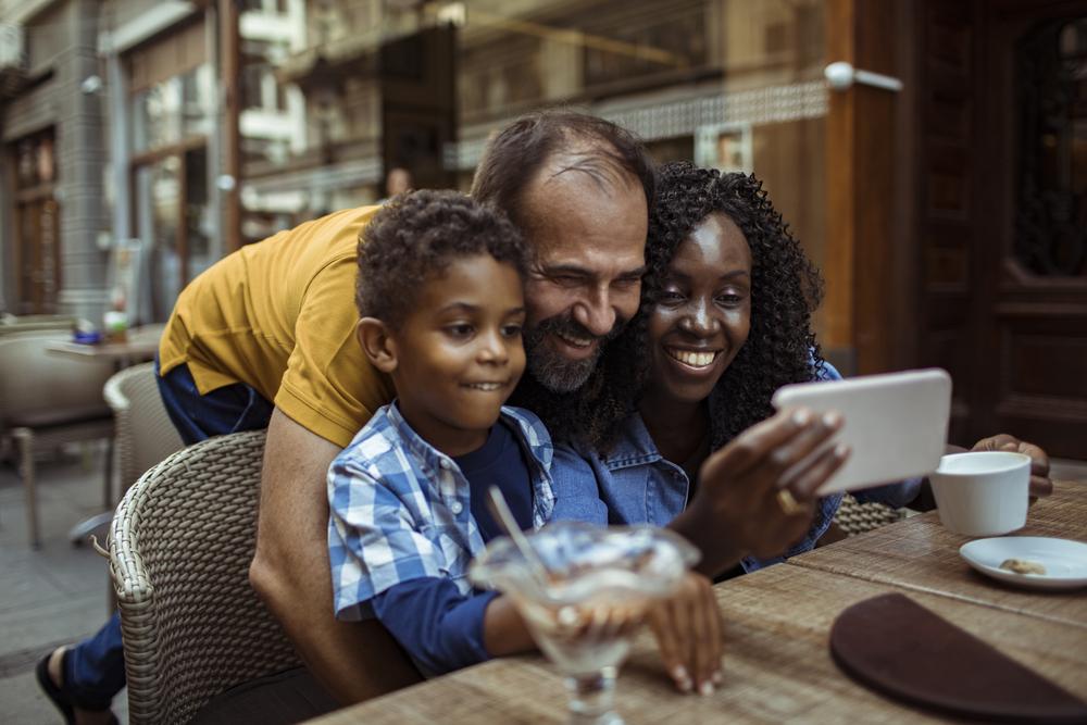 Um exemplo de como ser uma boa madrasta: uma mulher se diverte em um café com o marido e o enteado, e eles tiram foto juntos.