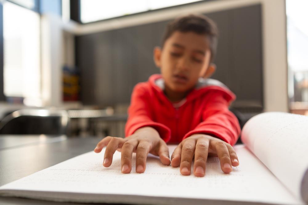 Um menino cego lê um livro em braille